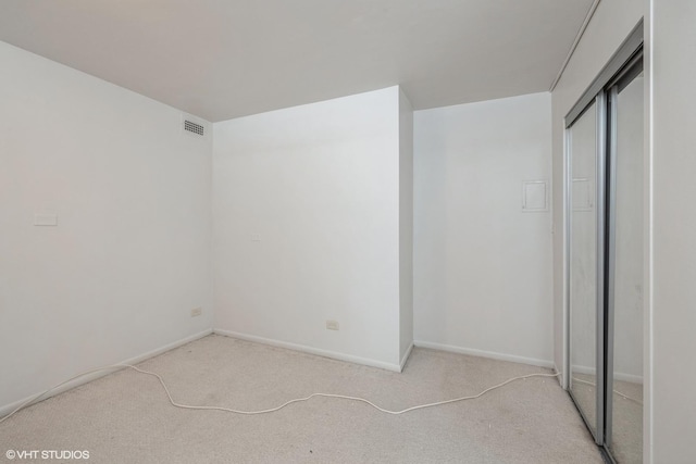 unfurnished bedroom featuring light carpet, a closet, visible vents, and baseboards