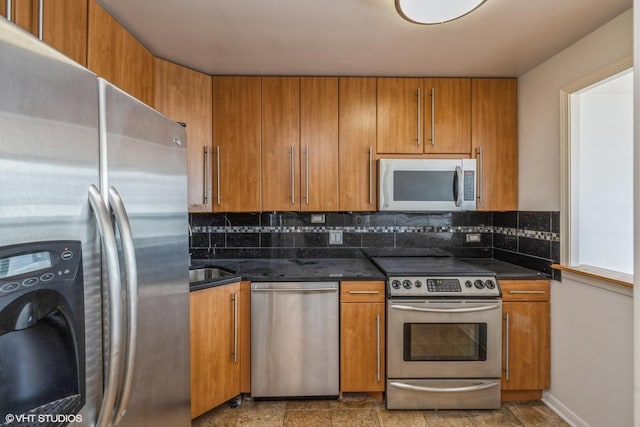 kitchen with appliances with stainless steel finishes, dark stone countertops, washer / dryer, and tasteful backsplash