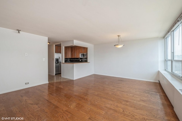 unfurnished living room featuring baseboards and wood finished floors