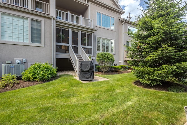 rear view of property featuring a yard and cooling unit