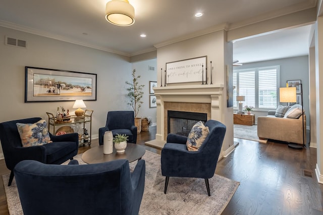 living room featuring a tile fireplace, crown molding, and hardwood / wood-style floors