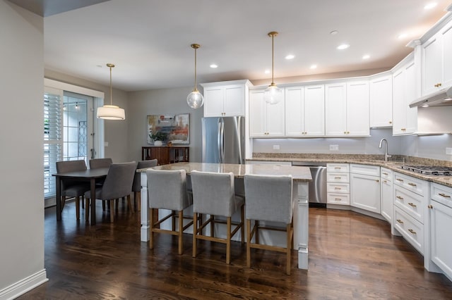 kitchen featuring pendant lighting, dark hardwood / wood-style flooring, stainless steel appliances, and white cabinetry