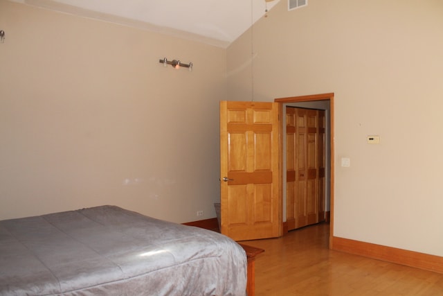 bedroom with wood-type flooring and a towering ceiling