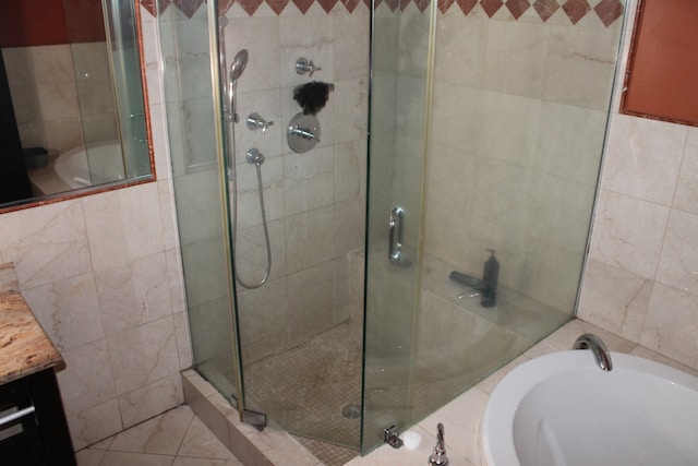 bathroom with separate shower and tub, vanity, and tile walls