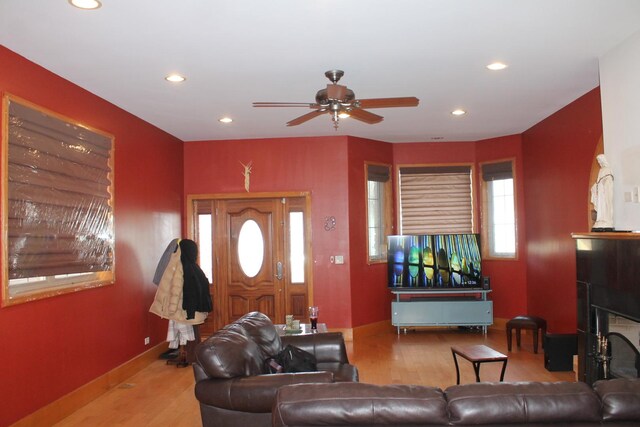 living room featuring ceiling fan, light wood-type flooring, and a tile fireplace