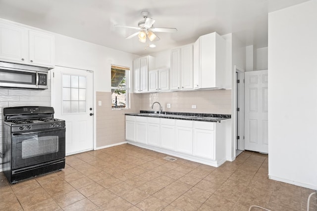 kitchen featuring white cabinets, sink, ceiling fan, black gas range oven, and light tile patterned flooring