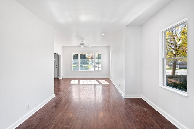 unfurnished living room featuring a wealth of natural light, ceiling fan, and dark wood-type flooring