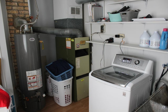 clothes washing area featuring washer / clothes dryer, dark hardwood / wood-style floors, and water heater