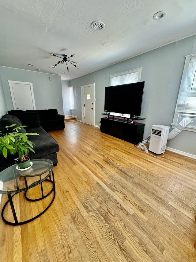 living room featuring ceiling fan, light hardwood / wood-style flooring, and a textured ceiling