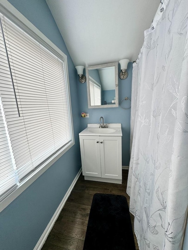 bathroom with hardwood / wood-style floors, vanity, and lofted ceiling