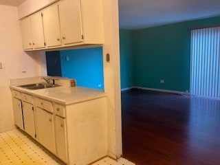 kitchen with light wood-type flooring, white cabinetry, and sink