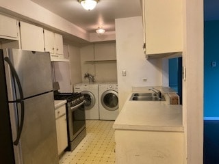 kitchen featuring washing machine and clothes dryer, sink, white cabinets, and stainless steel appliances