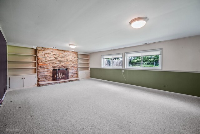 unfurnished living room featuring carpet flooring, a stone fireplace, and built in features