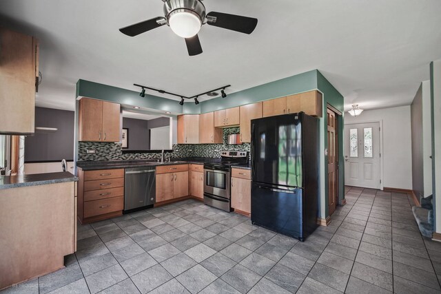 kitchen featuring sink, rail lighting, decorative backsplash, ceiling fan, and appliances with stainless steel finishes