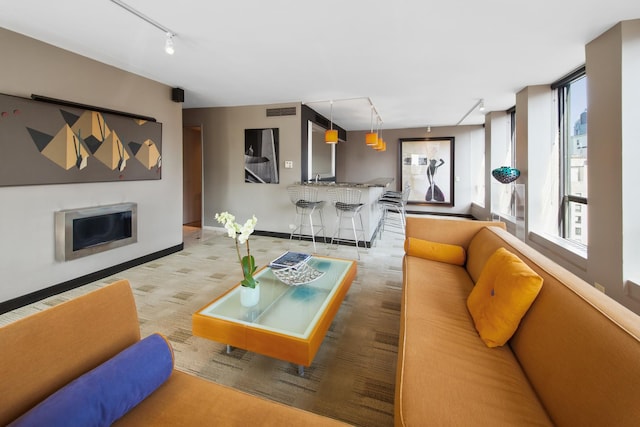 living area featuring carpet floors, a fireplace, visible vents, baseboards, and rail lighting