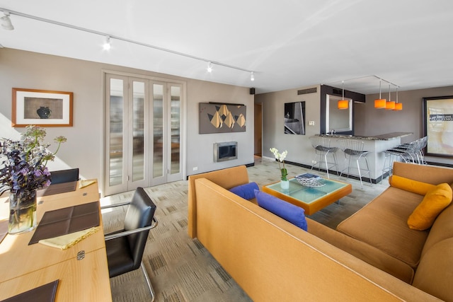 living area featuring rail lighting, visible vents, and a fireplace