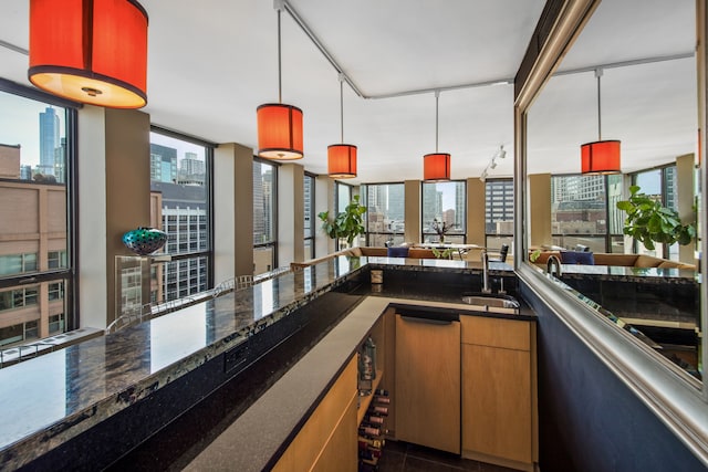 bar featuring sink, a wealth of natural light, a wall of windows, and pendant lighting