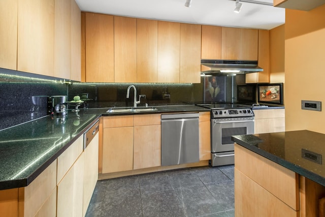 kitchen featuring under cabinet range hood, stainless steel appliances, a sink, backsplash, and dark stone counters