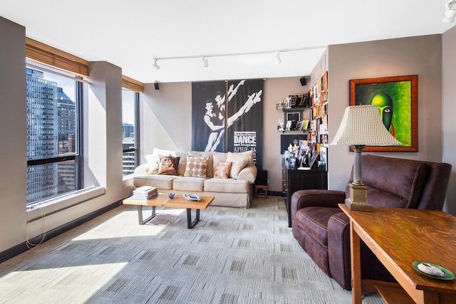 living area with light carpet, rail lighting, baseboards, and a city view