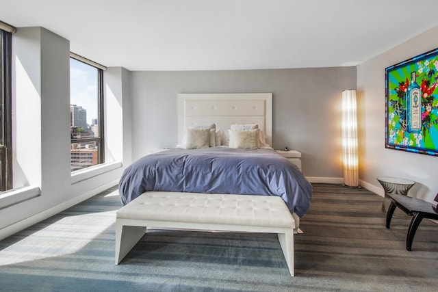 bedroom with baseboards, dark colored carpet, and a city view