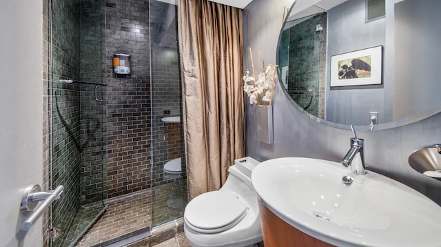 bathroom featuring a shower with door, vanity, and toilet