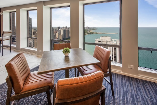 dining space with marble finish floor, a healthy amount of sunlight, a water view, and a city view