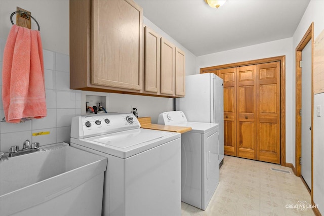 laundry area featuring cabinets, separate washer and dryer, tile walls, and sink