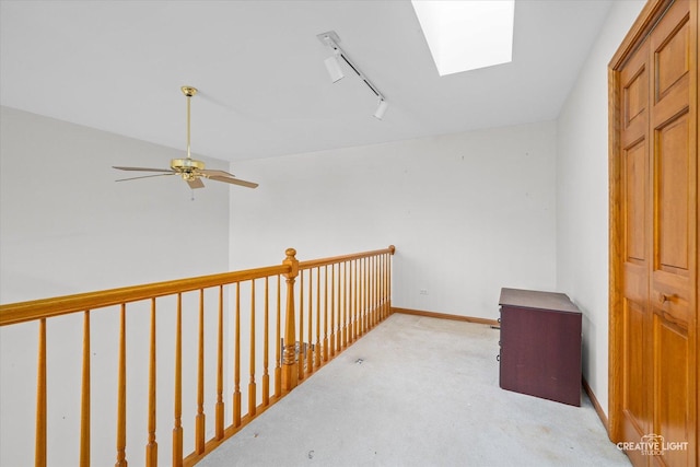 corridor featuring a skylight, light carpet, and rail lighting