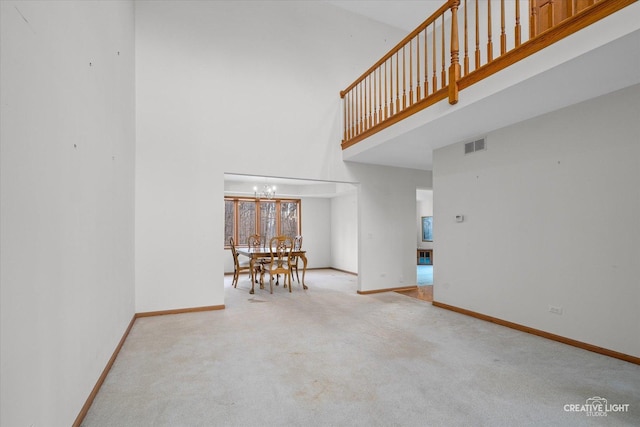 interior space featuring a high ceiling, light colored carpet, and an inviting chandelier