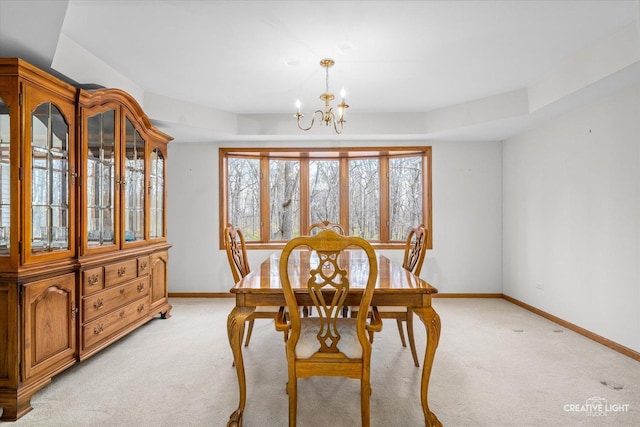 carpeted dining room featuring a raised ceiling and a chandelier