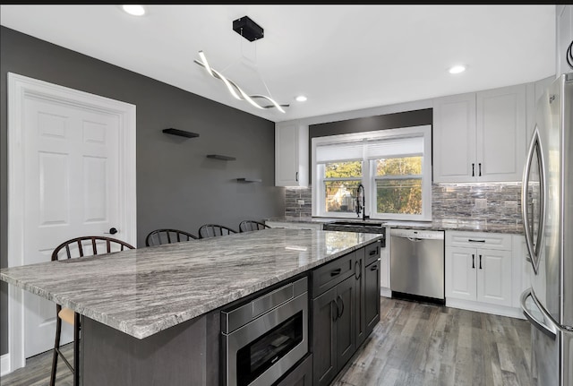 kitchen with a breakfast bar area, white cabinets, light wood-type flooring, and appliances with stainless steel finishes