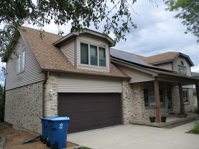 view of front of house featuring covered porch, solar panels, and a garage