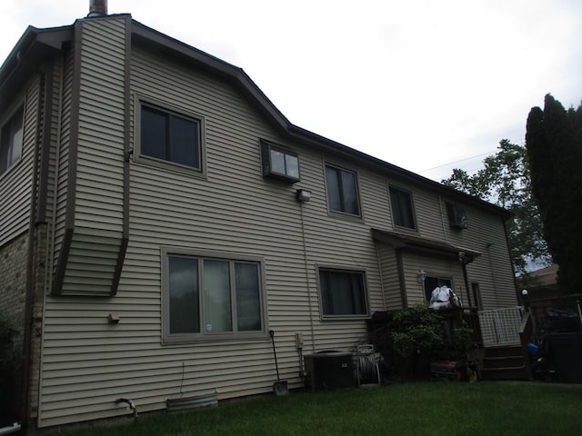 back of house featuring central AC unit and a lawn