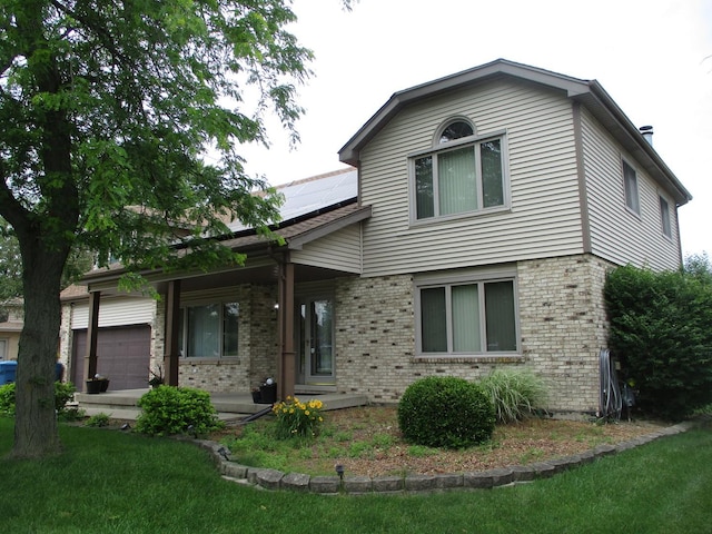 view of front of home with covered porch, brick siding, a garage, and roof mounted solar panels