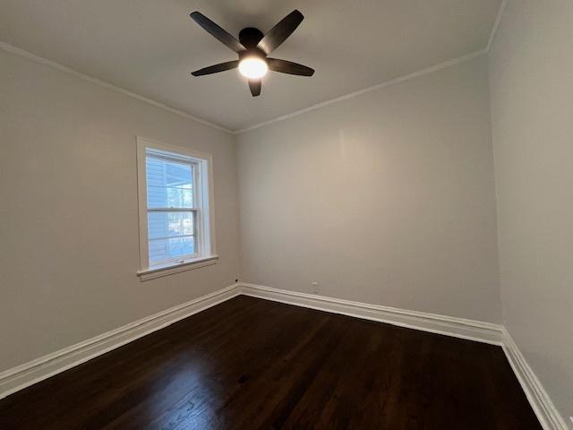 empty room featuring ceiling fan, baseboards, dark wood-style floors, and ornamental molding