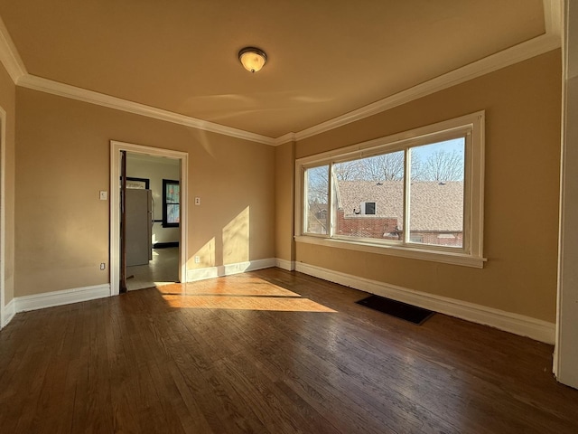 empty room featuring dark wood-type flooring, baseboards, and ornamental molding