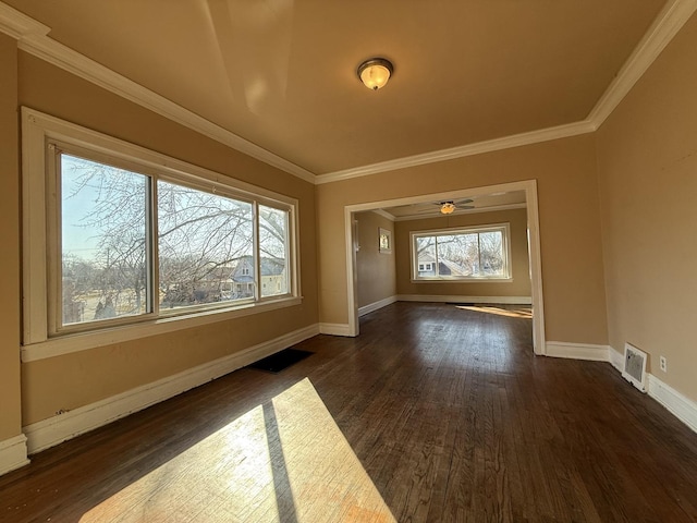 empty room featuring visible vents, baseboards, dark wood-type flooring, and ornamental molding