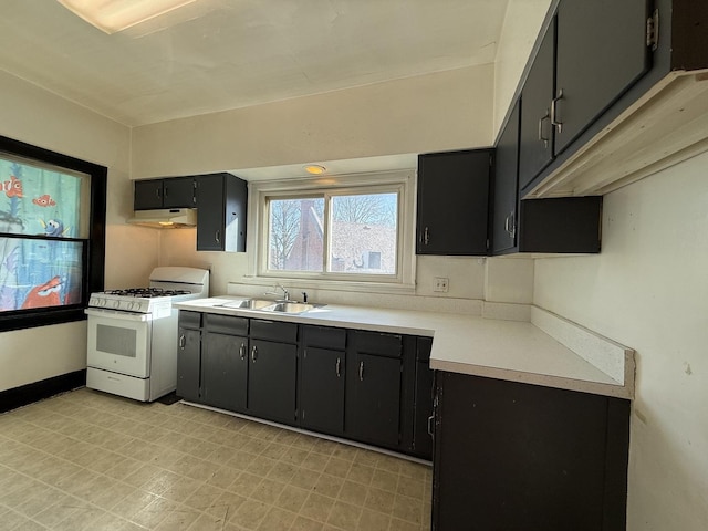 kitchen with light floors, white gas stove, a sink, light countertops, and under cabinet range hood