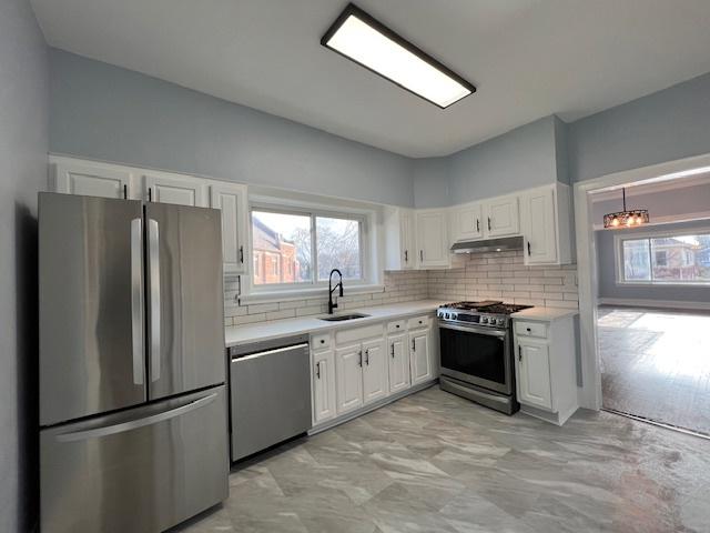 kitchen featuring white cabinetry, sink, stainless steel appliances, tasteful backsplash, and a chandelier