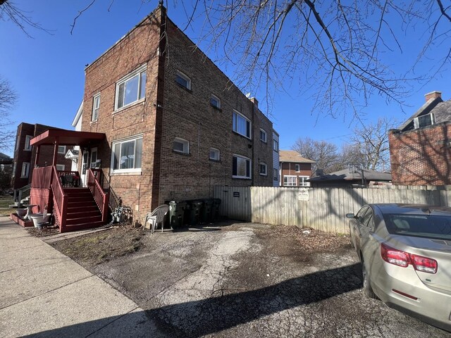 view of home's exterior featuring brick siding, stairs, and fence