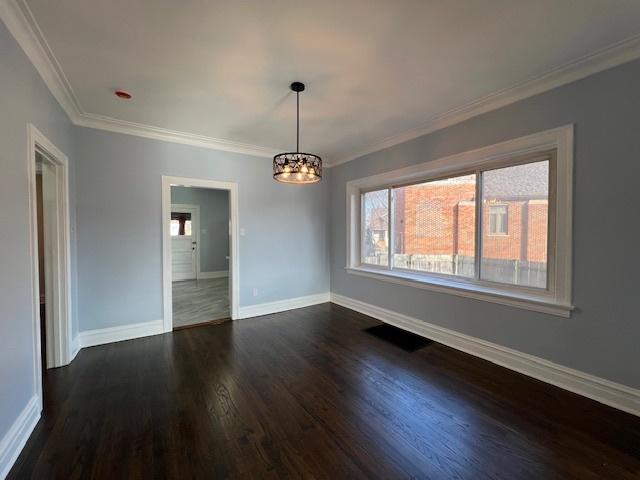 unfurnished room with dark wood-style floors, baseboards, a chandelier, and ornamental molding