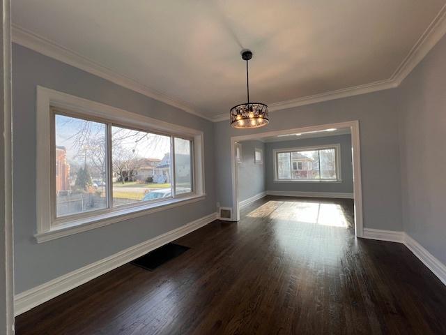 unfurnished dining area with dark wood finished floors, an inviting chandelier, baseboards, and a wealth of natural light