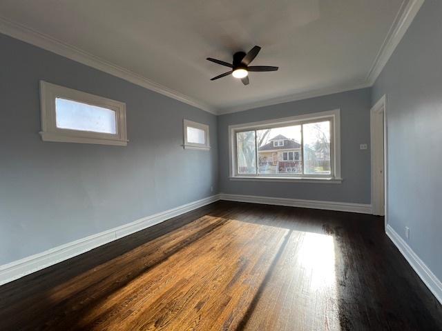 empty room with baseboards, dark wood finished floors, a ceiling fan, and ornamental molding