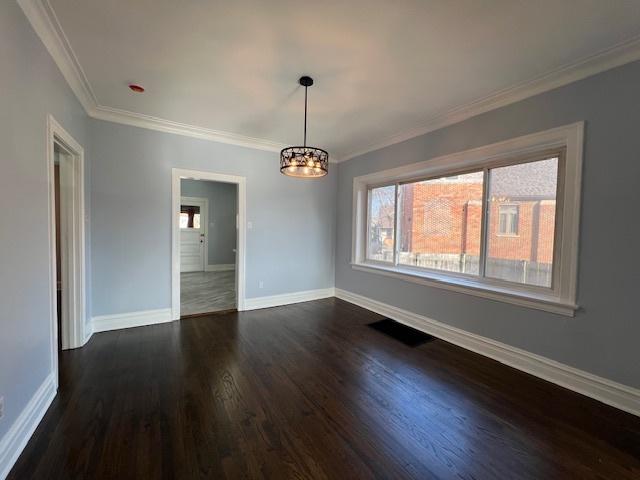 unfurnished room featuring a chandelier, dark hardwood / wood-style flooring, and ornamental molding