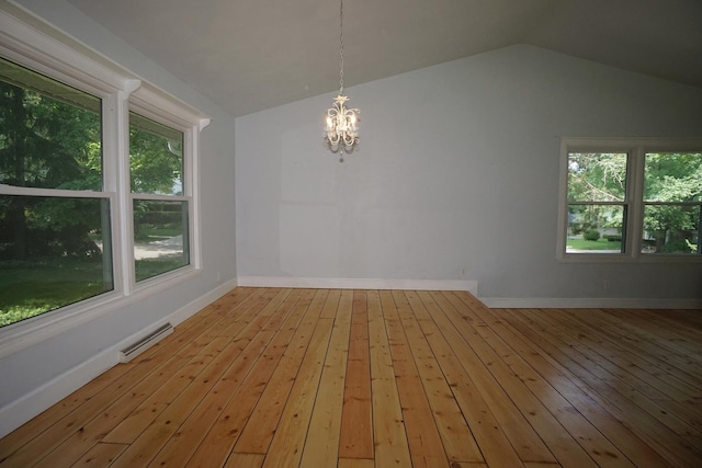 unfurnished room featuring vaulted ceiling, plenty of natural light, a notable chandelier, and light wood-type flooring