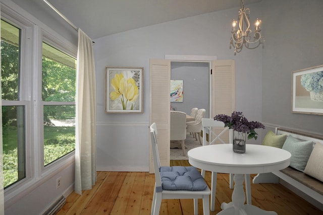 dining space with a notable chandelier, plenty of natural light, light hardwood / wood-style floors, and vaulted ceiling