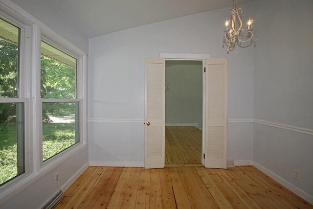 spare room with a chandelier, light hardwood / wood-style flooring, and lofted ceiling