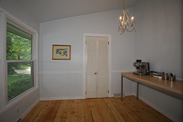 interior space featuring a notable chandelier, vaulted ceiling, and light wood-type flooring