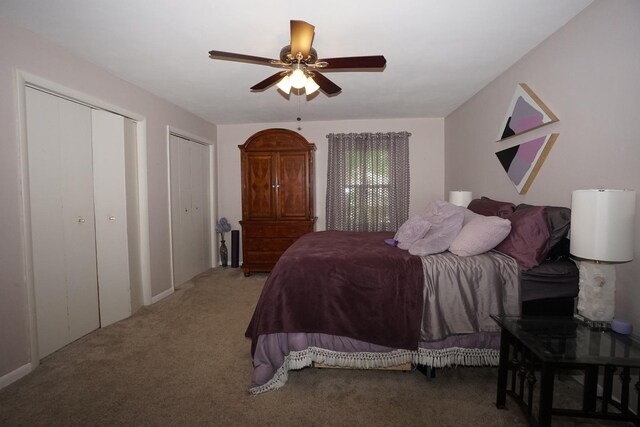 bedroom with carpet flooring, ceiling fan, and two closets