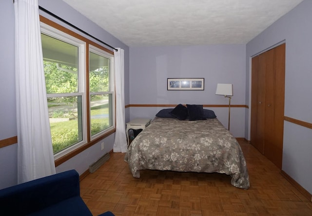 bedroom featuring parquet flooring and a closet